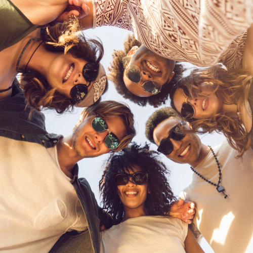 Multiethnic group of friends huddle join in a circle and looking down outdoors Multiethnic group of friends huddle join in a circle and looking down outdoors
